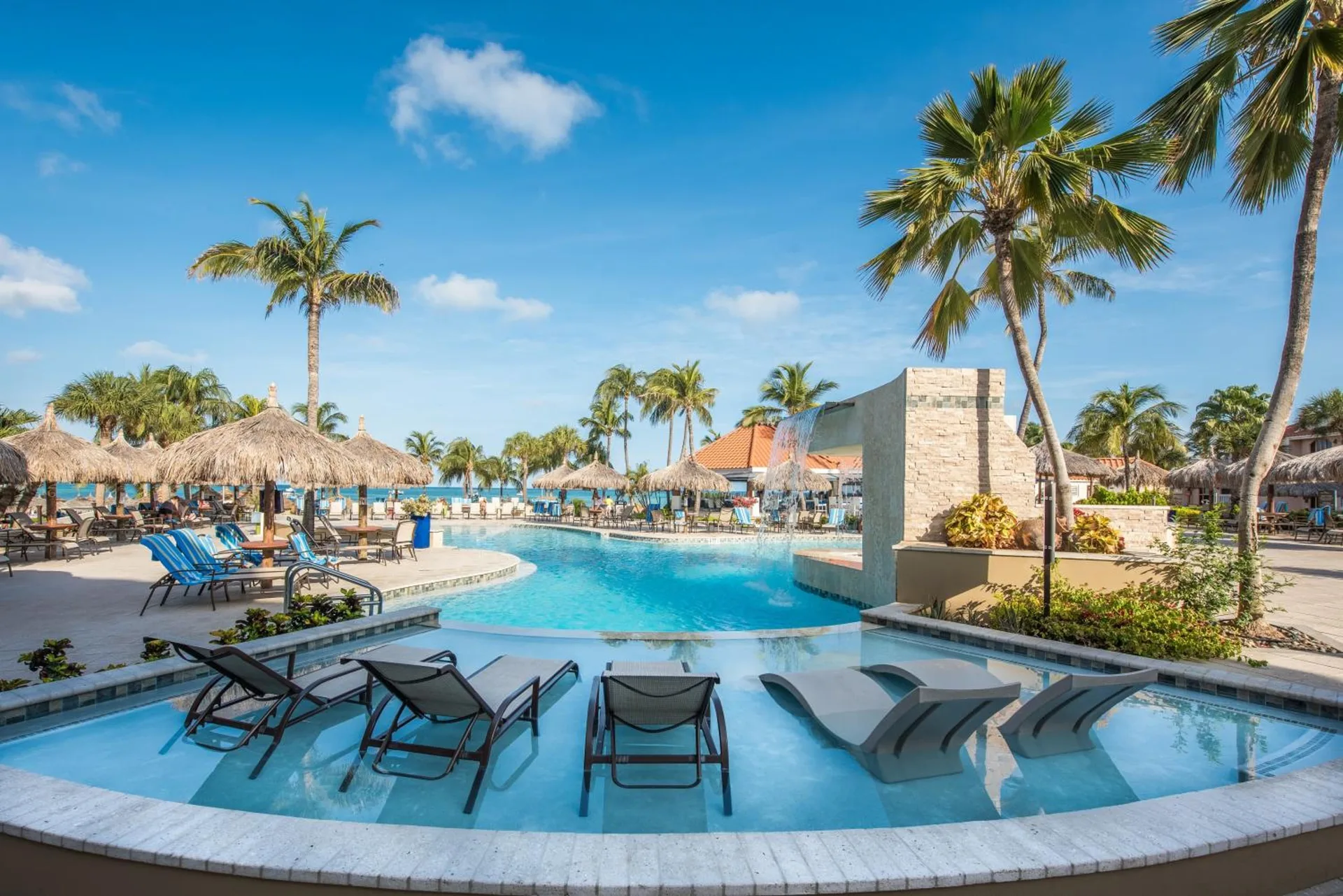 Resort pool with in-water loungers and palapas at Playa Linda Beach Resort.