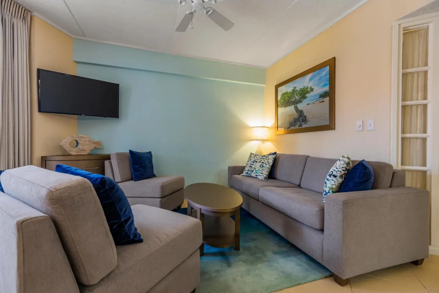 Living area with sofas, TV, and beach artwork at Playa Linda Beach Resort.