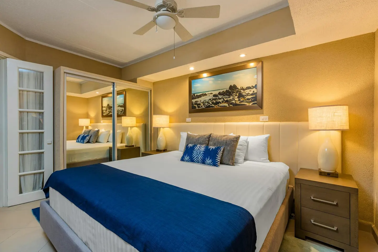 One Bedroom Suite king bedroom with ceiling fan and mirrored closet at Playa Linda Beach Resort.