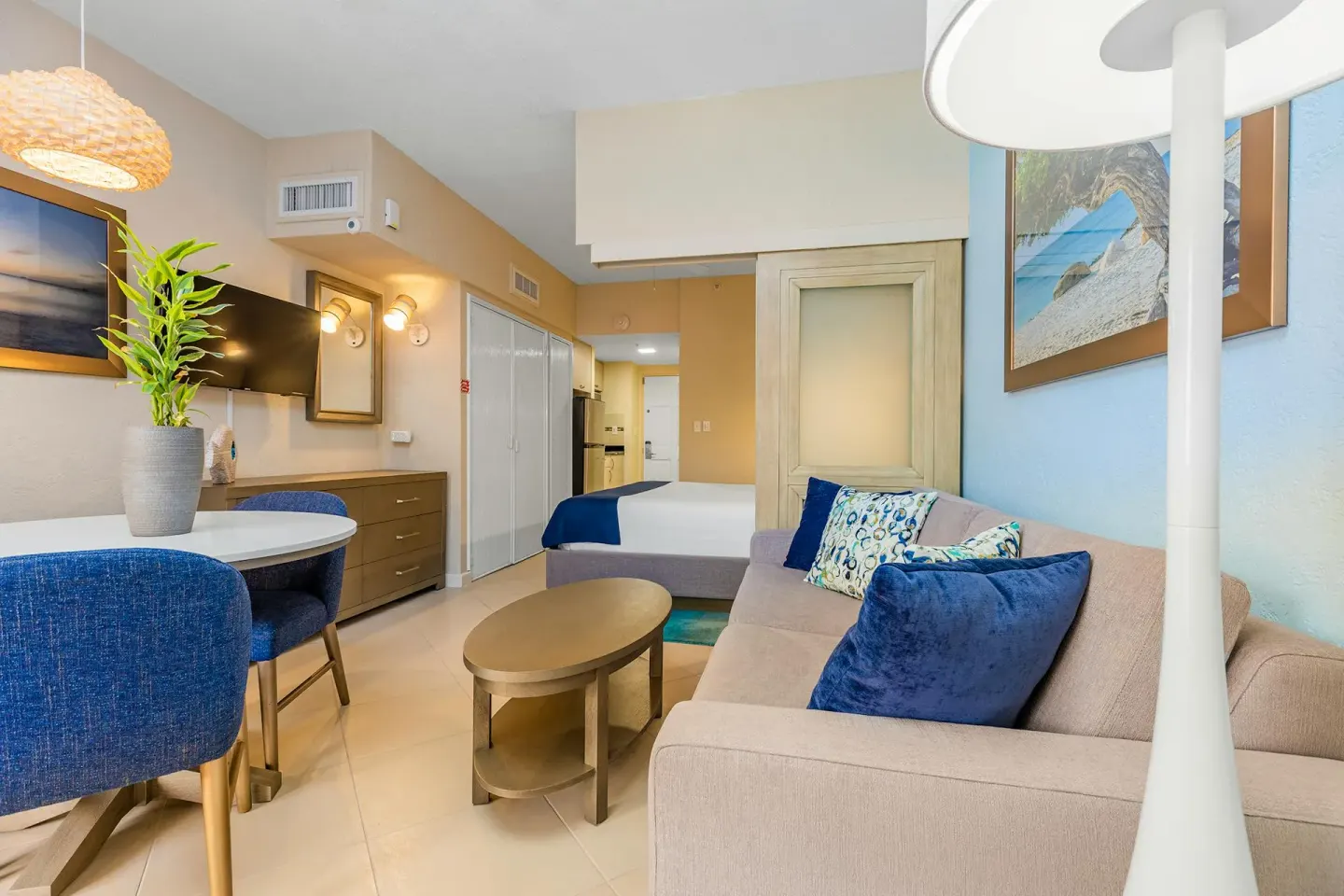 Studio Suite living area with sofa, round dining table and queen bed at Playa Linda Beach Resort.