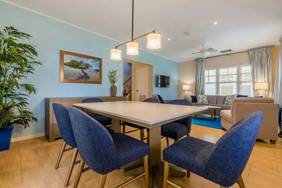Dining table with blue chairs under pendant lights in the Townhouse Three Bedroom at Playa Linda Beach Resort.