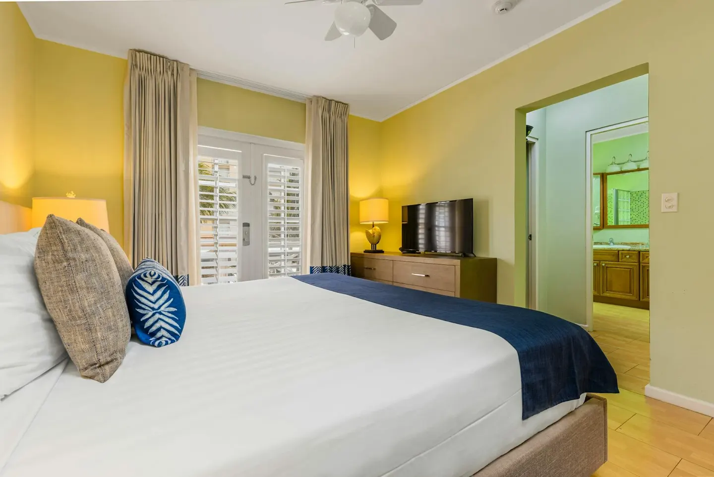 King bedroom with plantation-shuttered doors and en-suite bathroom in the Townhouse Three Bedroom at Playa Linda Beach Resort.