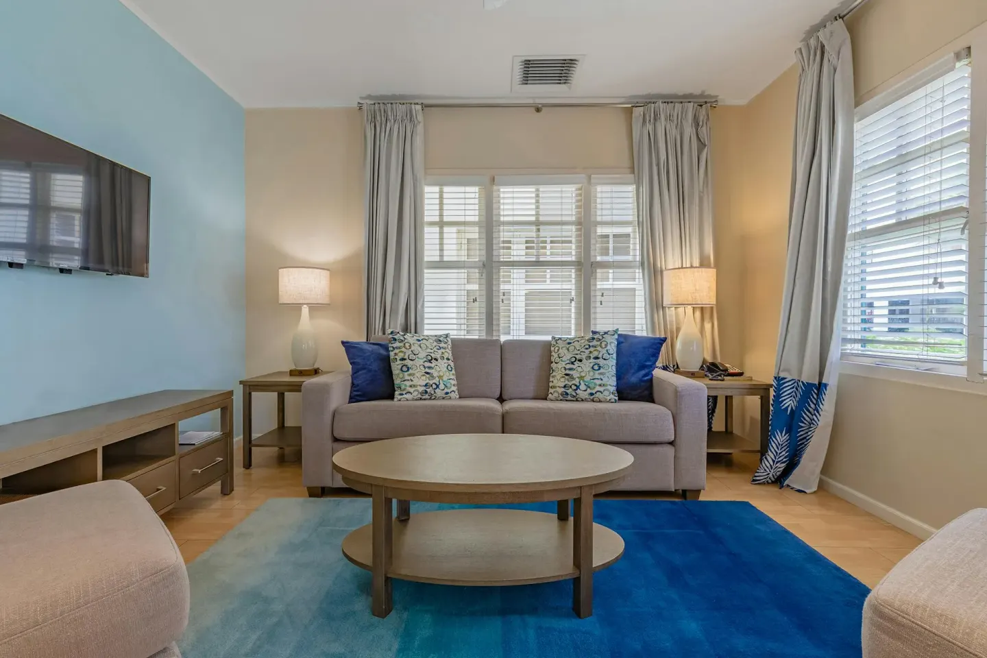 Living room with sofa and armchairs on a blue rug in the Townhouse Three Bedroom at Playa Linda Beach Resort.