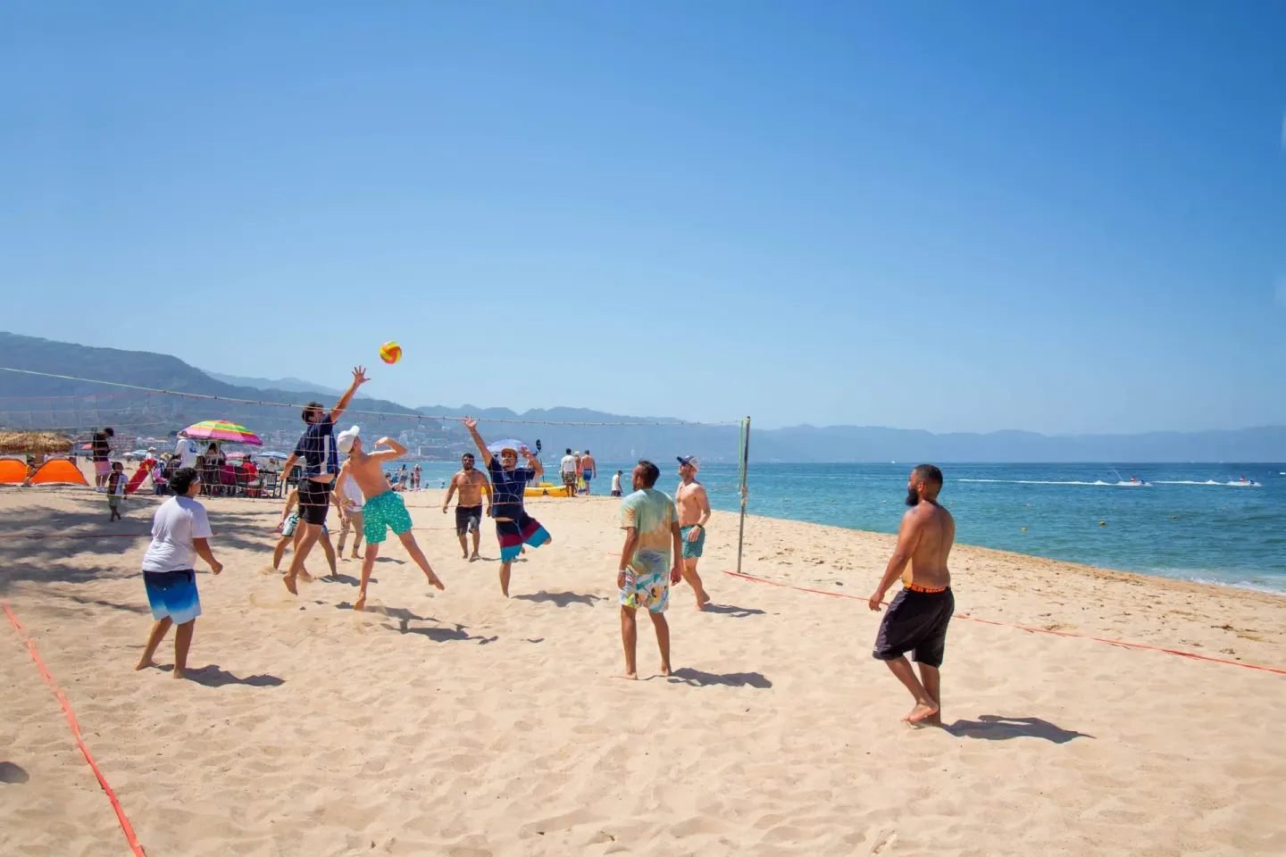 Guests play beach volleyball by the ocean at Plaza Pelicanos Club Beach Resort.