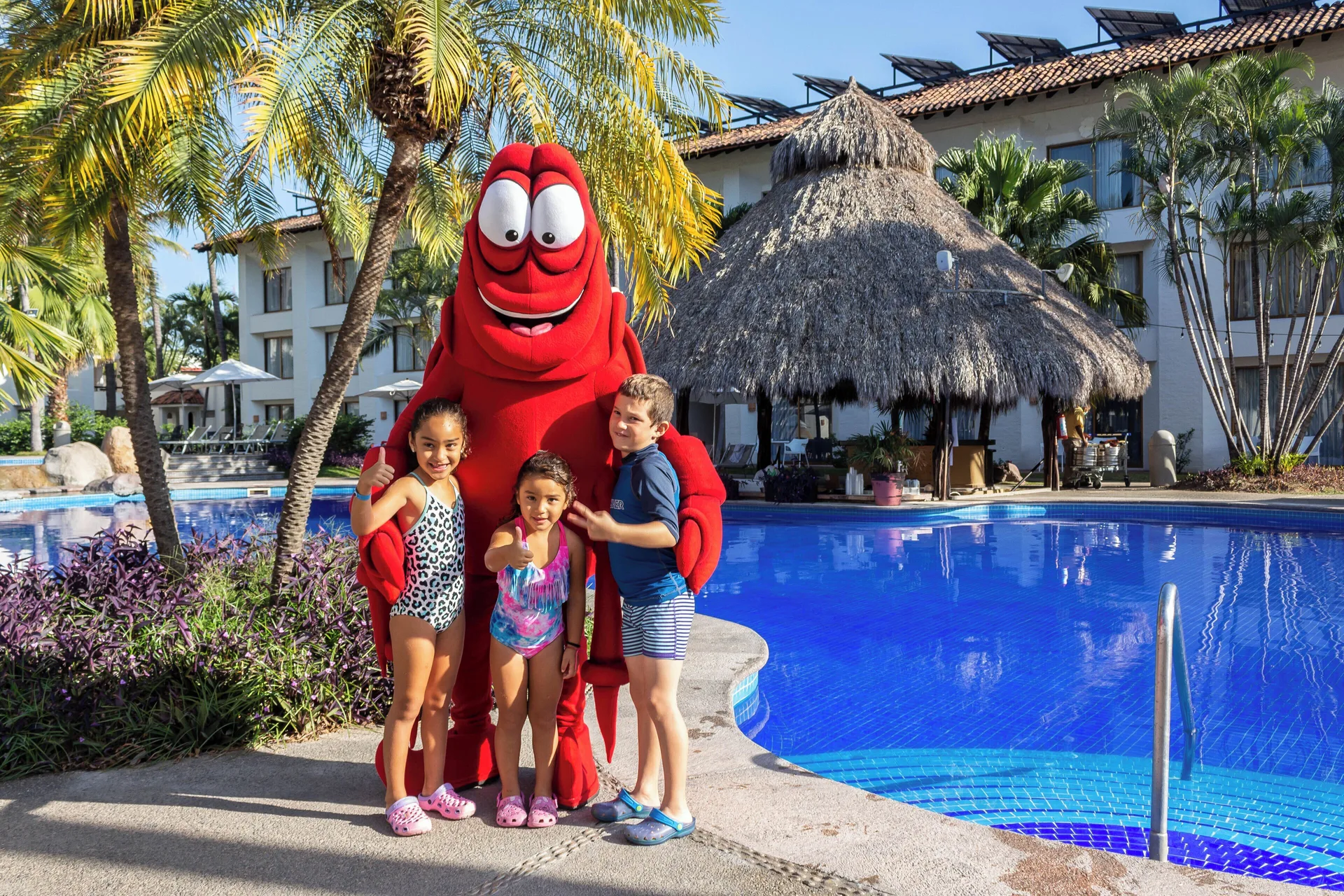Children with a red mascot beside the pool at Plaza Pelicanos Club Beach Resort.