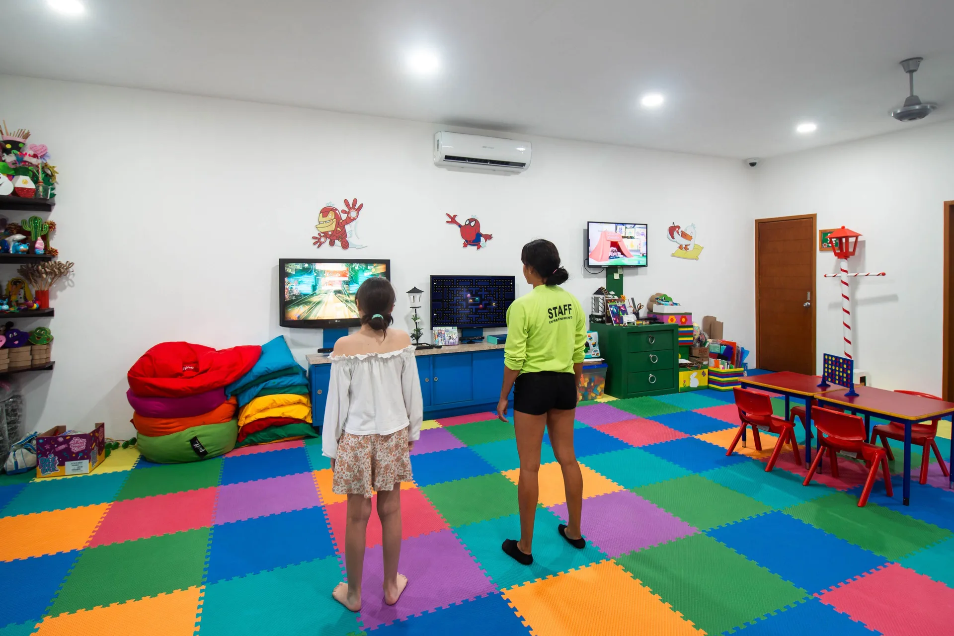 Staff member and child playing video games in the kids' room at Plaza Pelicanos Club Beach Resort.