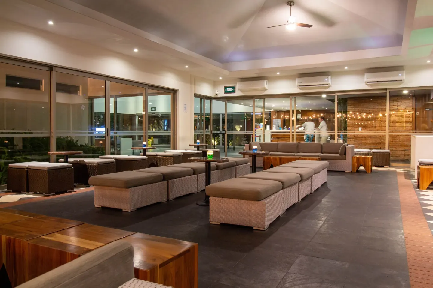 Lounge seating with tables and glass walls at Plaza Pelicanos Club Beach Resort.