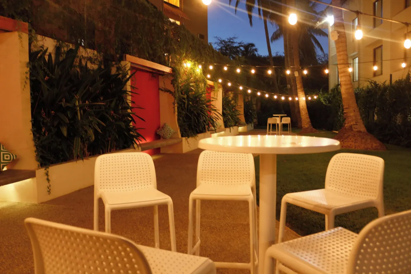 Outdoor seating with string lights and palms at Plaza Pelicanos Club Beach Resort.