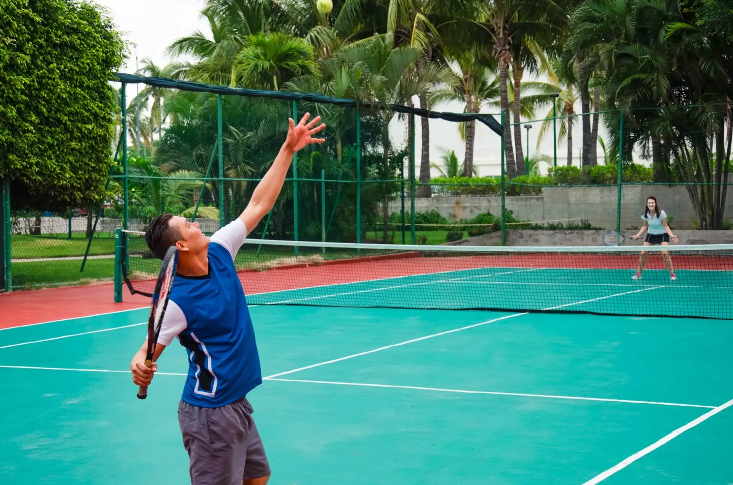 Guests play tennis on an outdoor court at Plaza Pelicanos Club Beach Resort.