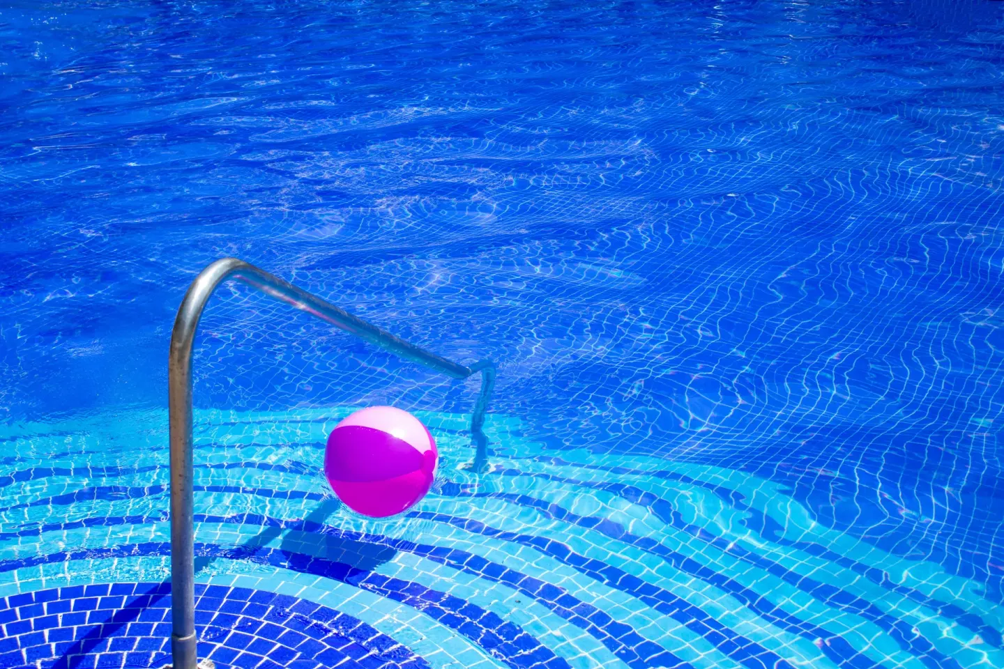 Blue pool steps with a handrail and beach ball at Plaza Pelicanos Club Beach Resort.
