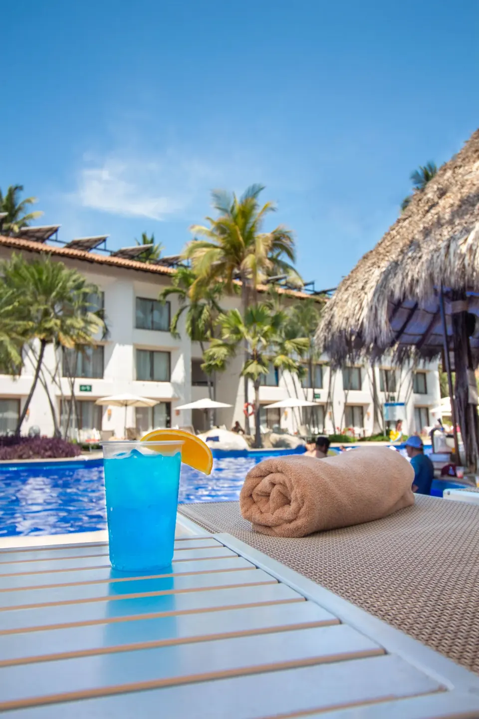 Blue drink and rolled towel beside the pool at Plaza Pelicanos Club Beach Resort.