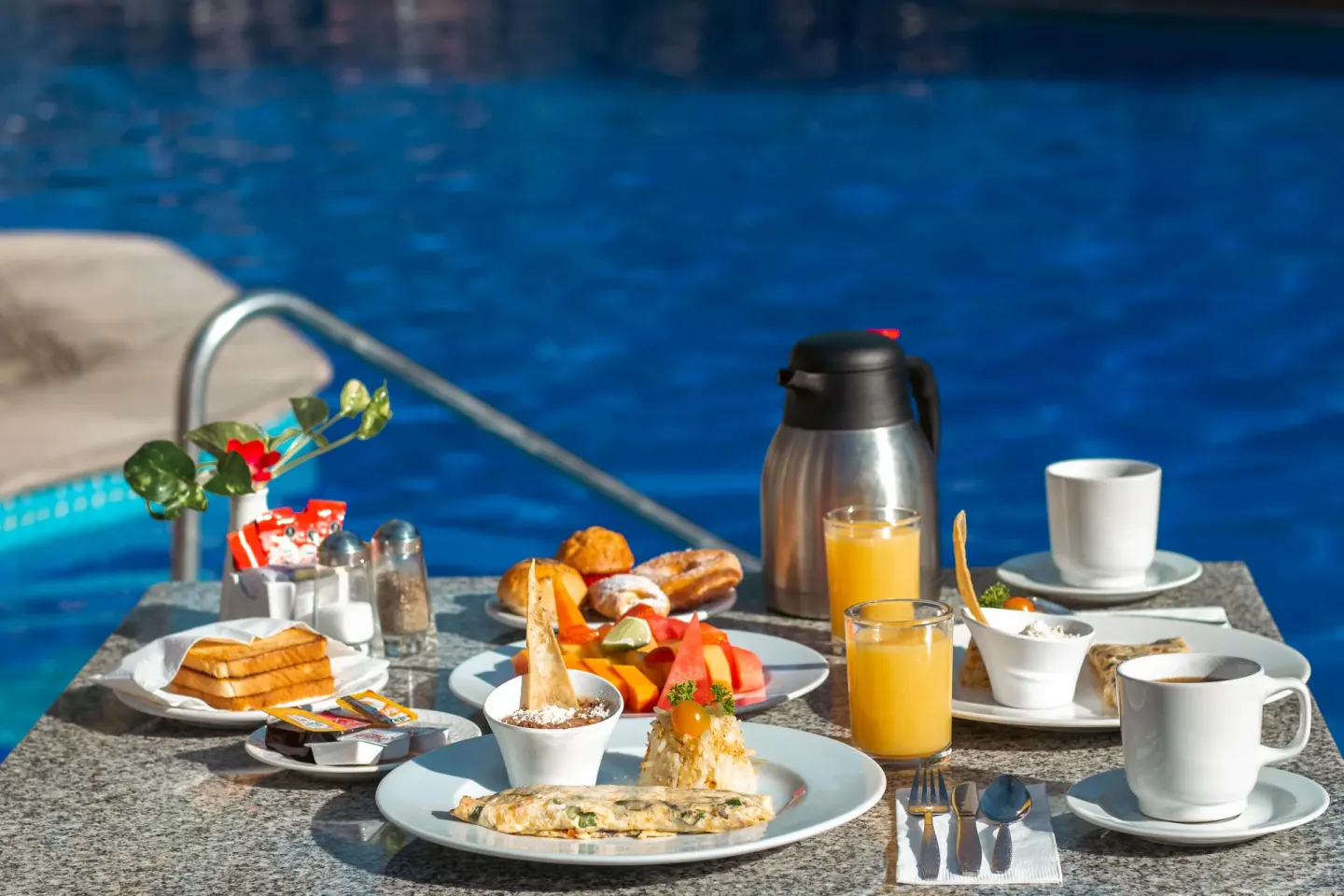 Breakfast plates and drinks set by the pool at Plaza Pelicanos Club Beach Resort.