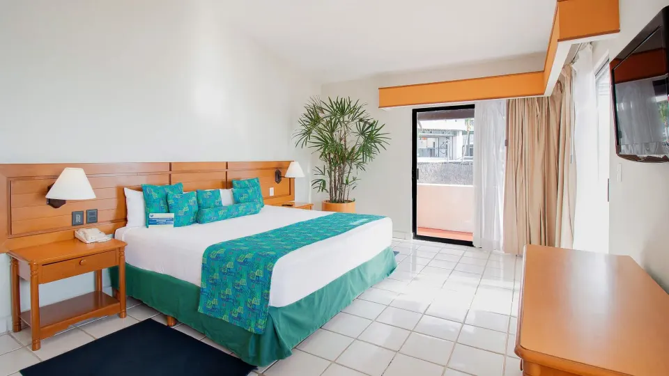 Standard bedroom with king bed and balcony at Plaza Pelicanos Club Beach Resort.