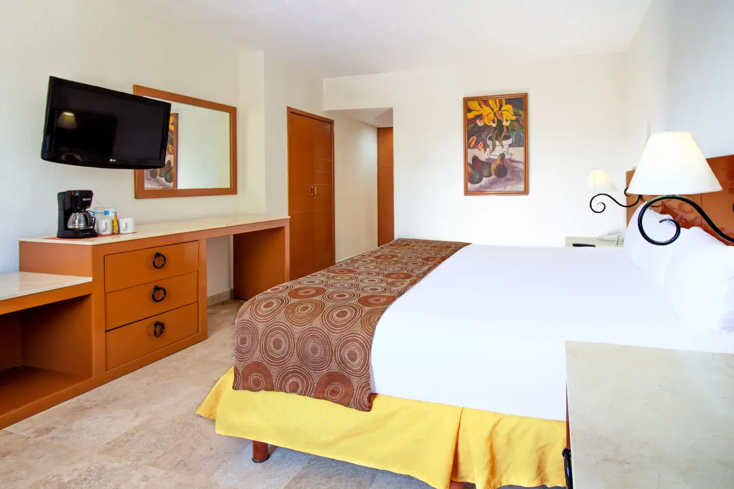 Standard room king bed with dresser and wall art at Plaza Pelicanos Club Beach Resort.