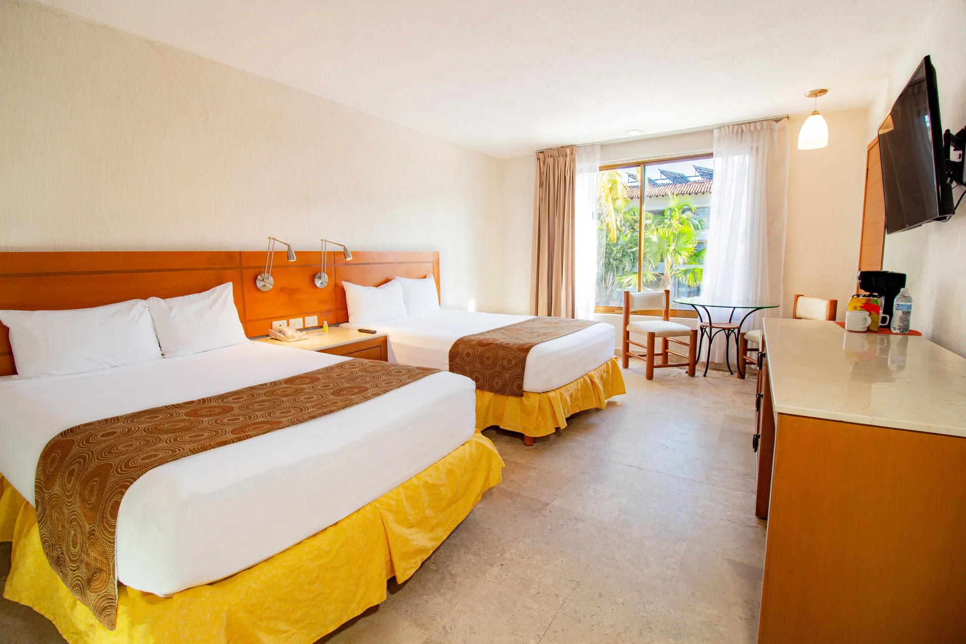 Standard Room with two beds, TV, and window table at Plaza Pelicanos Club Beach Resort.