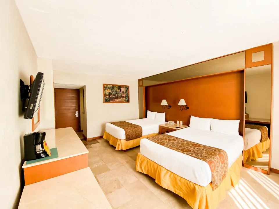 Standard room with two double beds and mirrored headboard at Plaza Pelicanos Club Beach Resort.