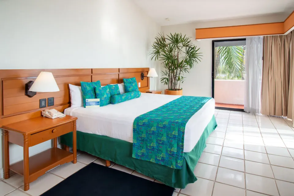 One-bedroom suite king bed and balcony at Plaza Pelicanos Club Beach Resort.