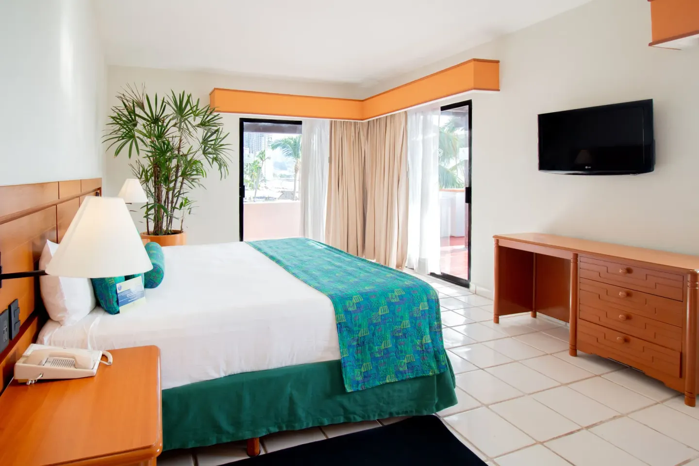 One-bedroom suite king bed with balcony doors at Plaza Pelicanos Club Beach Resort.