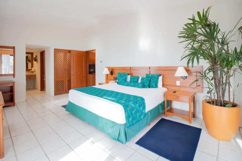 One-bedroom suite king bed near closet and bath area at Plaza Pelicanos Club Beach Resort.