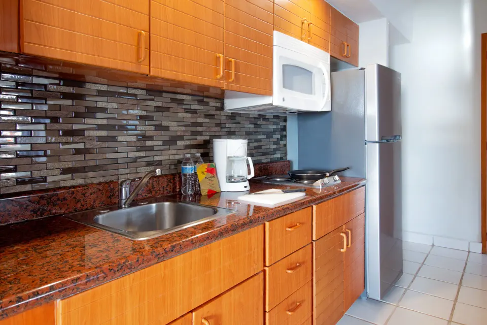 One-bedroom suite kitchenette with sink and refrigerator at Plaza Pelicanos Club Beach Resort.