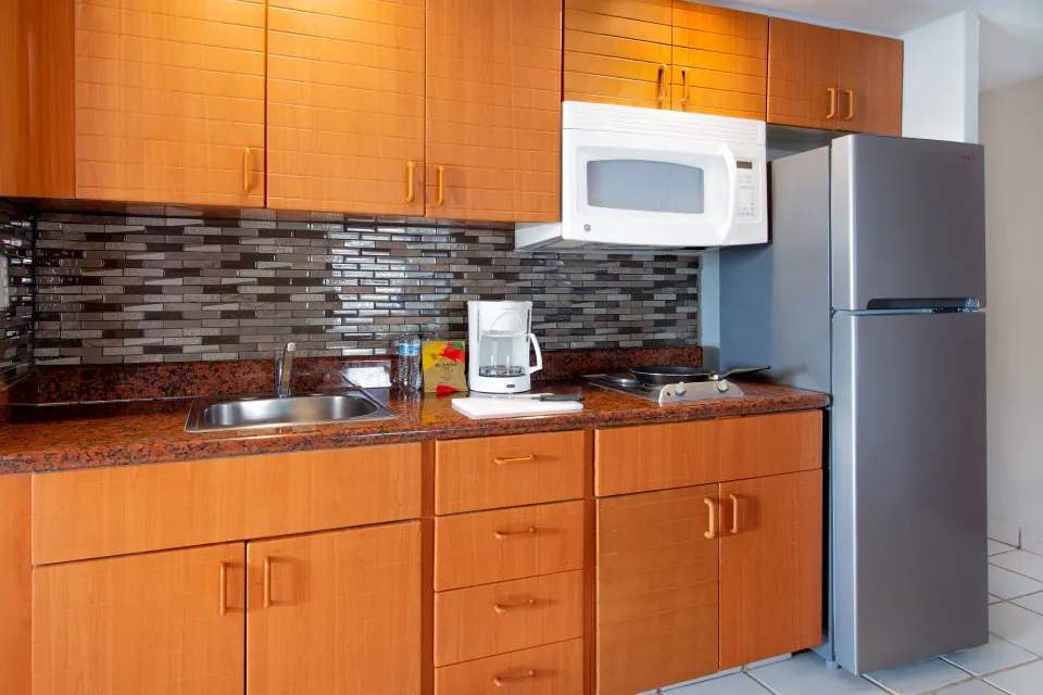 One-bedroom suite kitchenette with dining items at Plaza Pelicanos Club Beach Resort.