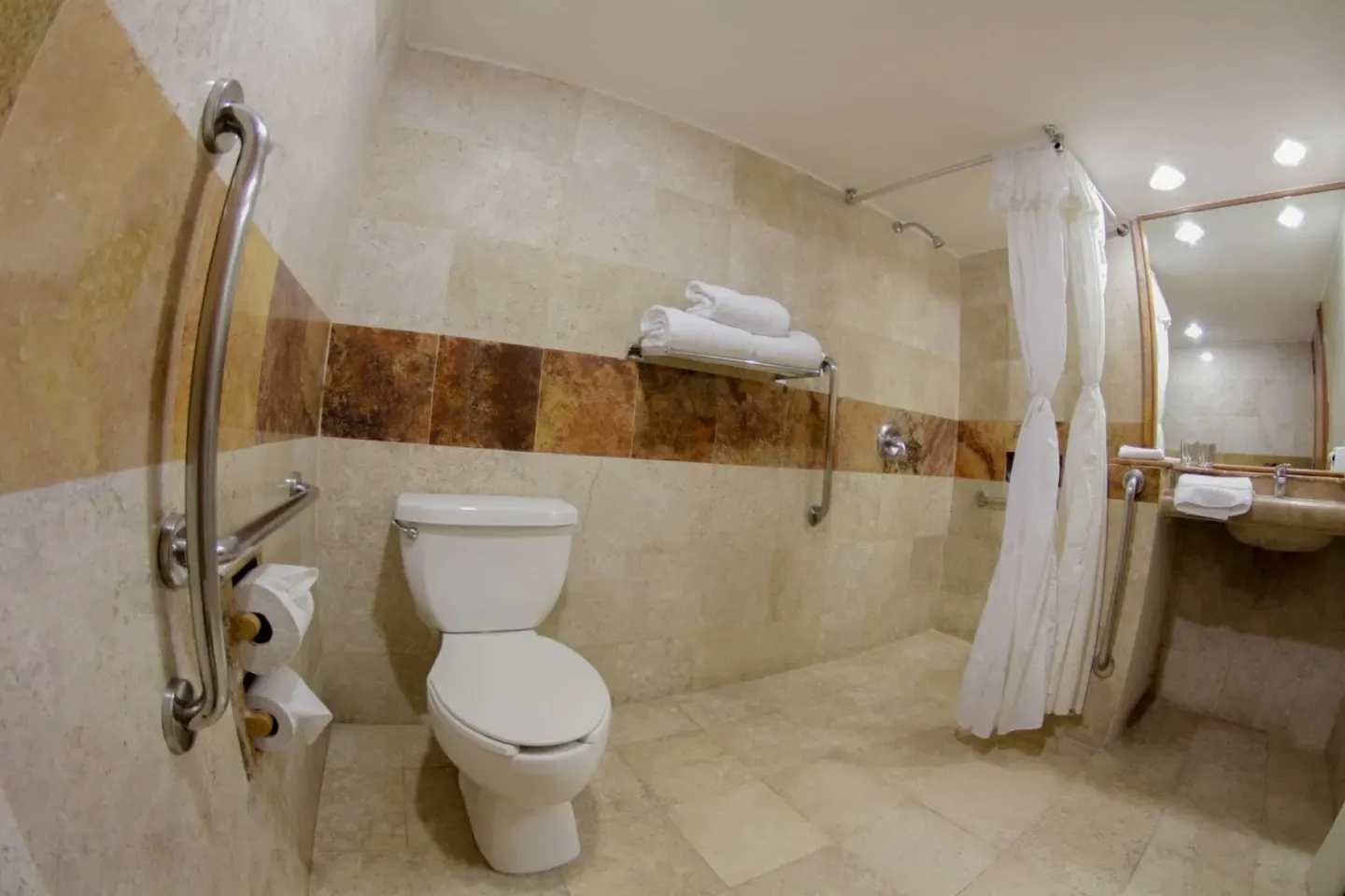 Superior Room accessible bathroom at Plaza Pelicanos Club Beach Resort with toilet, shower curtain and grab bars.