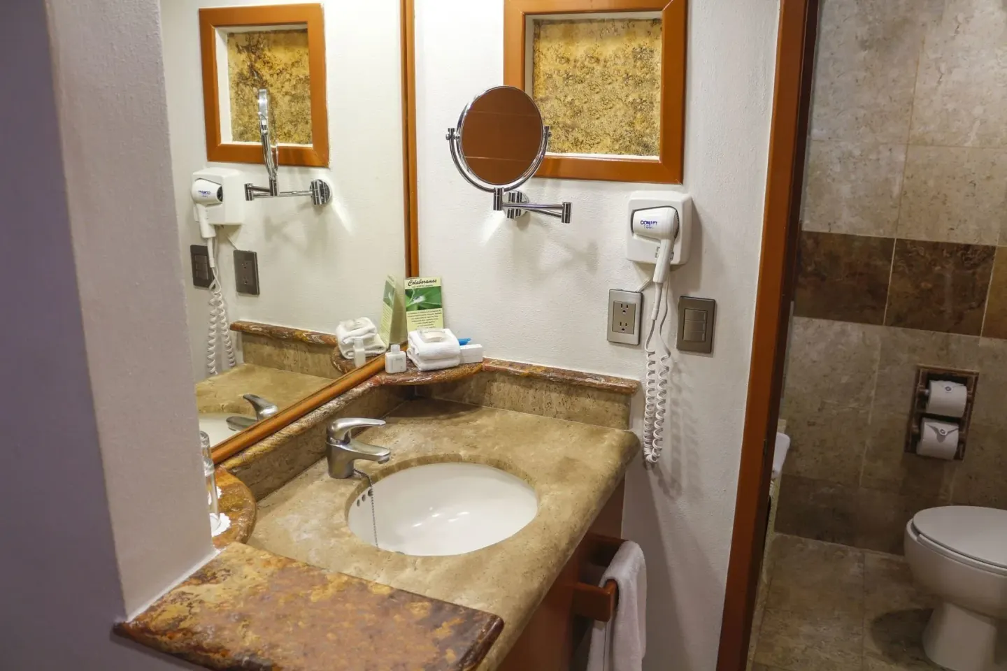 Superior Room bathroom vanity at Plaza Pelicanos Club Beach Resort with sink, mirror and toilet area.