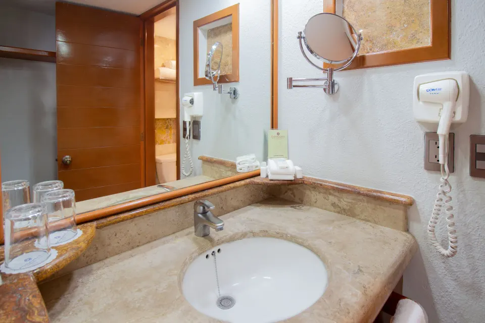 Superior Room bathroom vanity with mirror and sink at Plaza Pelicanos Club Beach Resort.