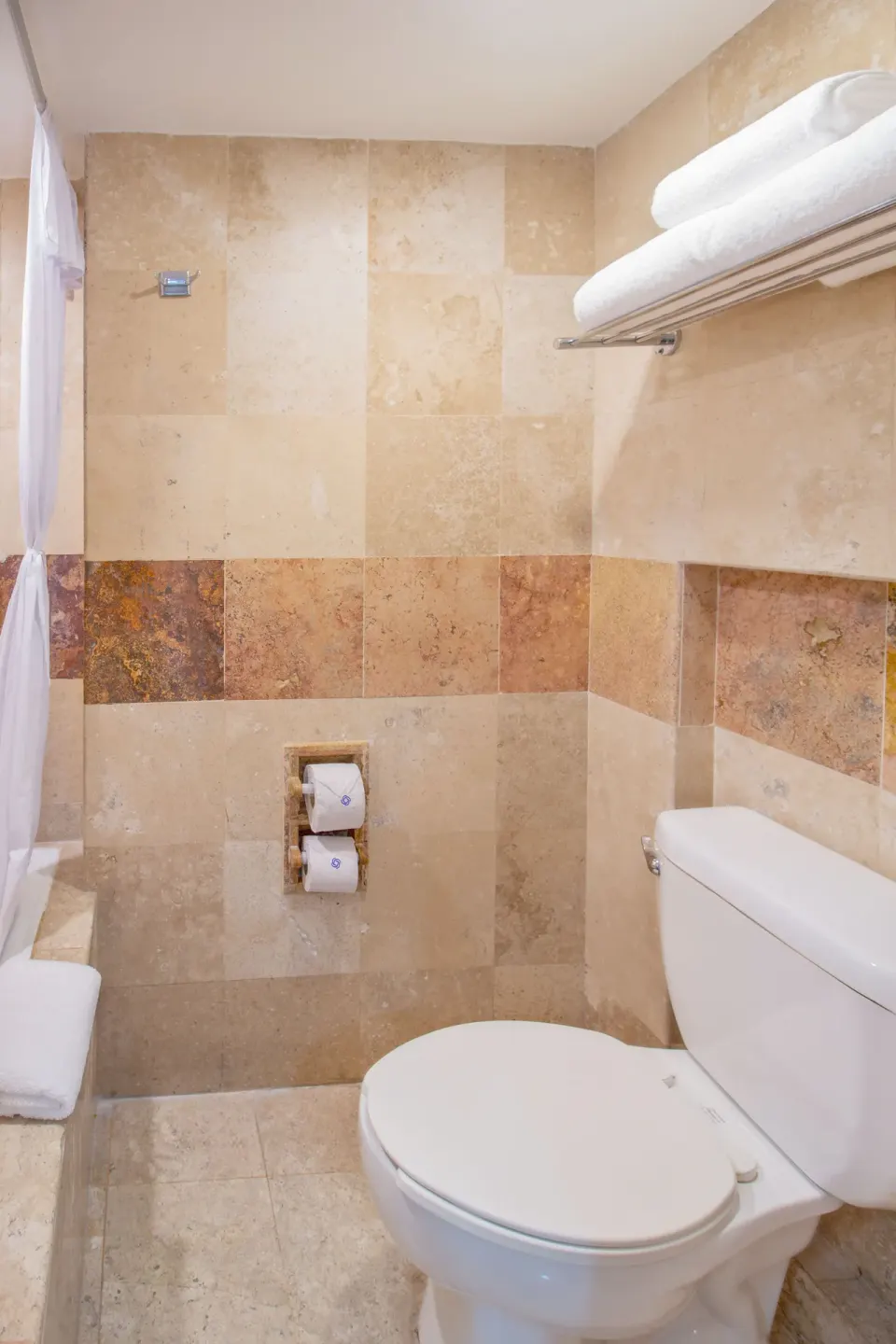 Superior Room bathroom with toilet, shower curtain, and towel shelf at Plaza Pelicanos Club Beach Resort.