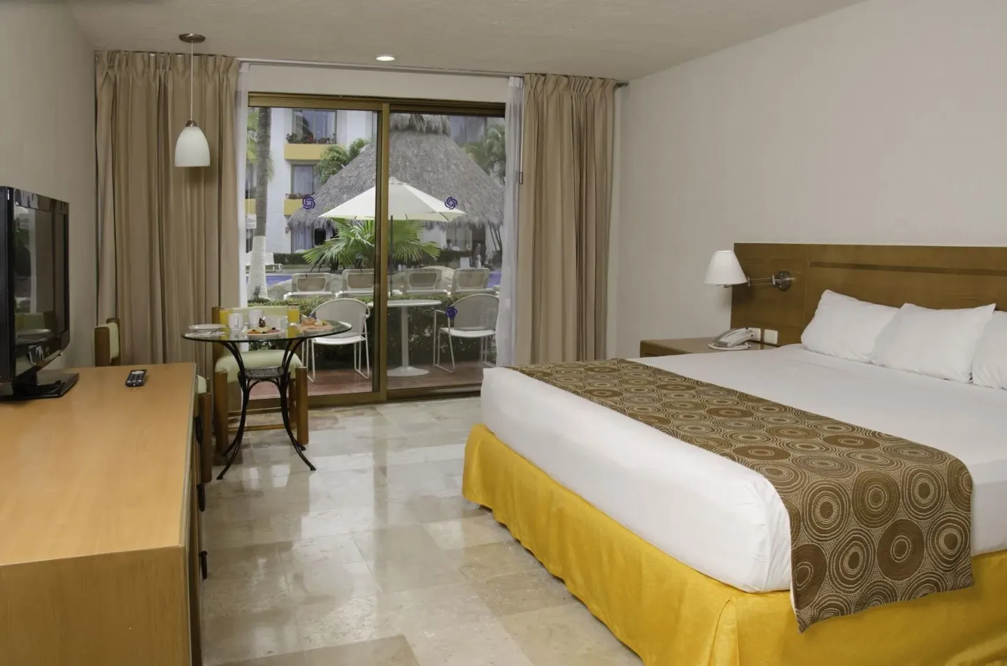 Superior room with king bed, TV, table, and balcony at Plaza Pelicanos Club Beach Resort.