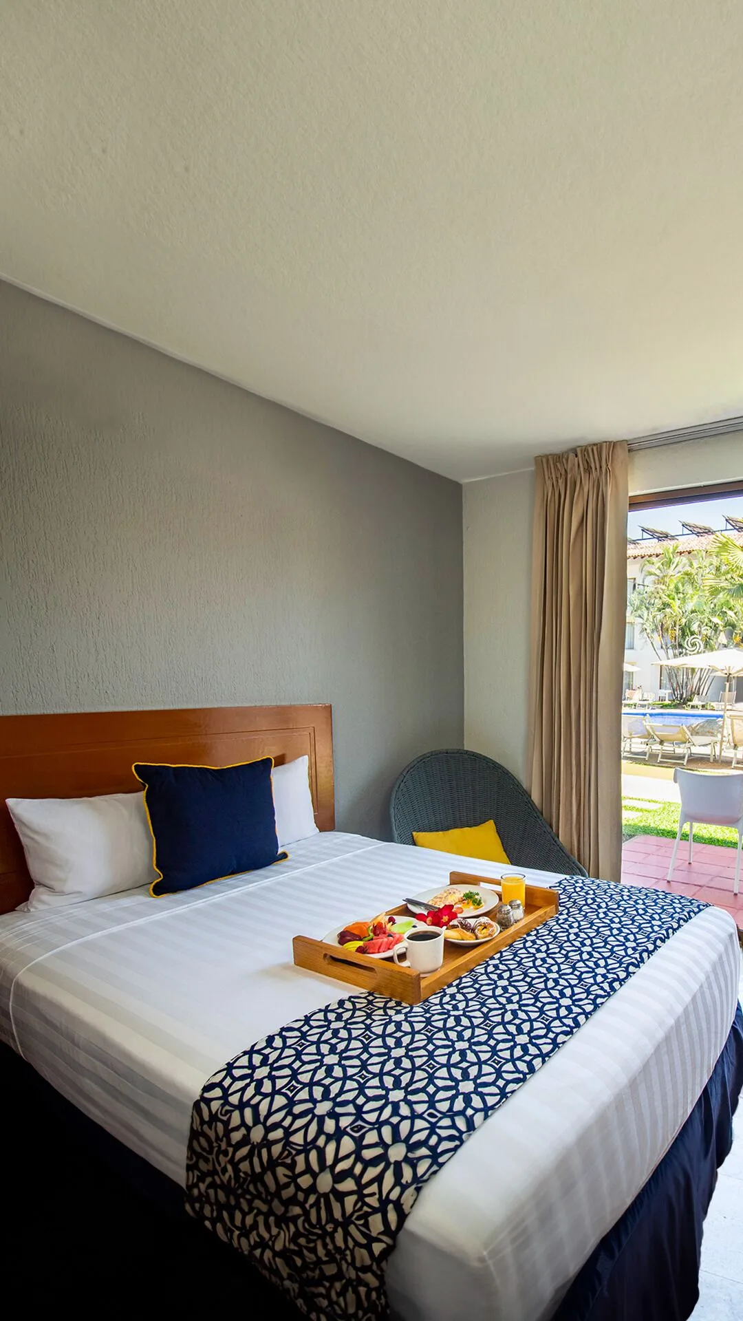 Superior Room king bed with breakfast tray near patio doors at Plaza Pelicanos Club Beach Resort.