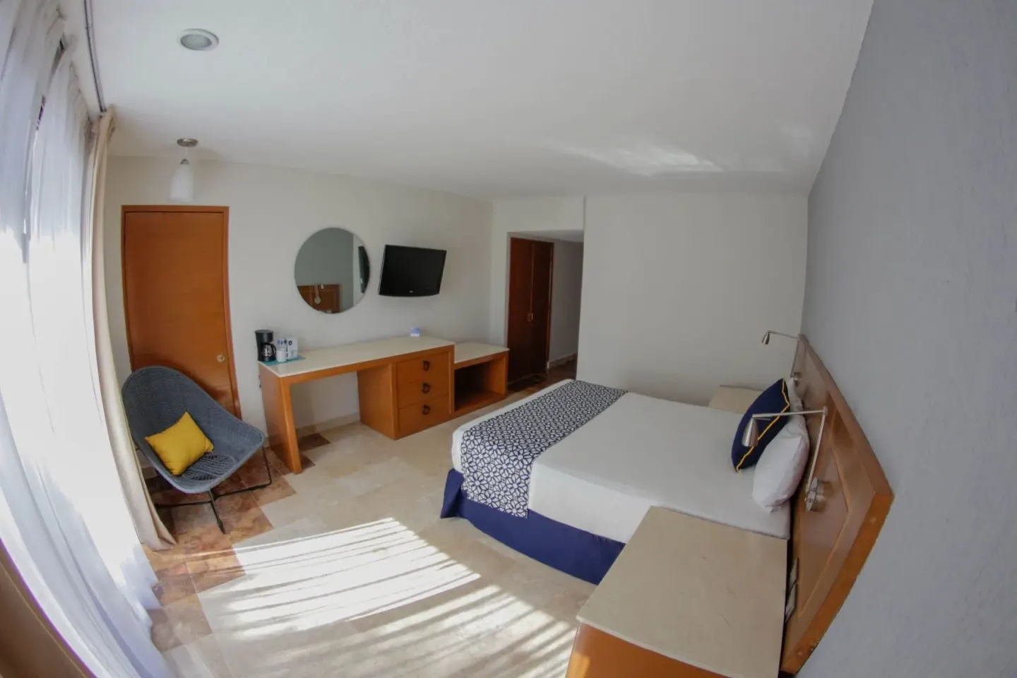 Superior room with king bed, chair, desk, mirror, and TV at Plaza Pelicanos Club Beach Resort.