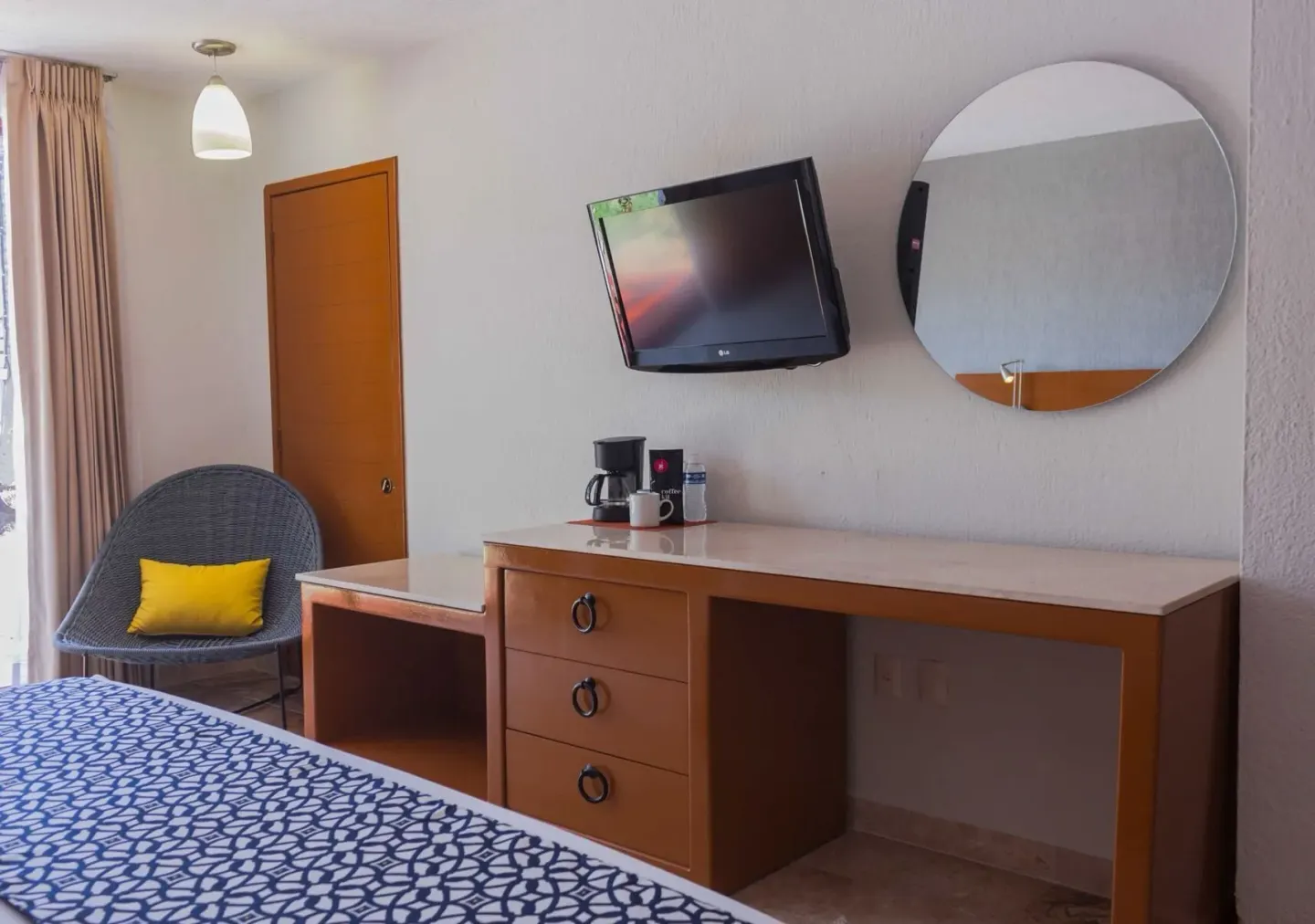 Superior room desk, TV, round mirror, and chair at Plaza Pelicanos Club Beach Resort.