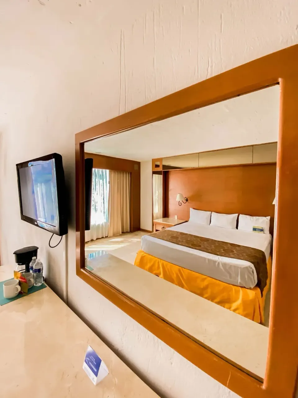 Superior room mirror reflecting a king bed at Plaza Pelicanos Club Beach Resort.