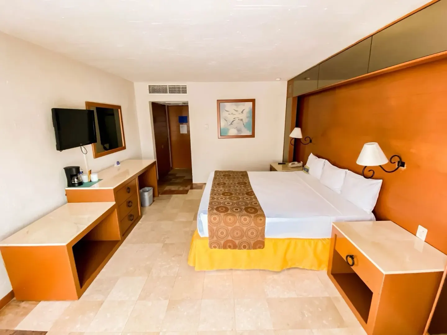 Superior room with king bed, desks, TV, and orange wood accents at Plaza Pelicanos Club Beach Resort.