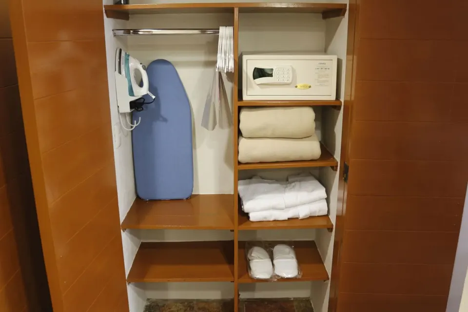 Superior Room closet at Plaza Pelicanos Club Beach Resort with open shelves, safe and ironing board.
