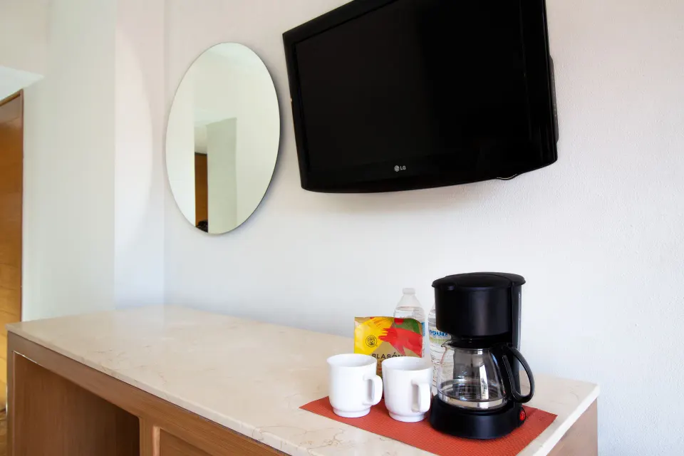 Superior Room coffee maker, mugs, mirror, and wall TV at Plaza Pelicanos Club Beach Resort.