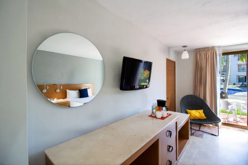 Superior Room dresser, TV, mirror, and lounge chair at Plaza Pelicanos Club Beach Resort.