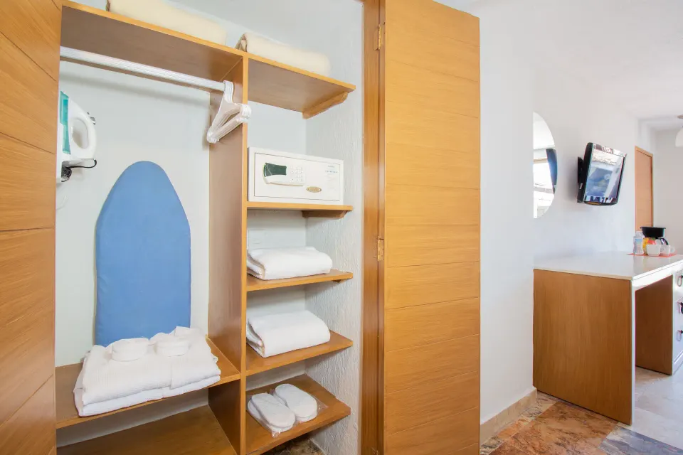 Superior Room open closet with towels, safe, iron, and shelves at Plaza Pelicanos Club Beach Resort.