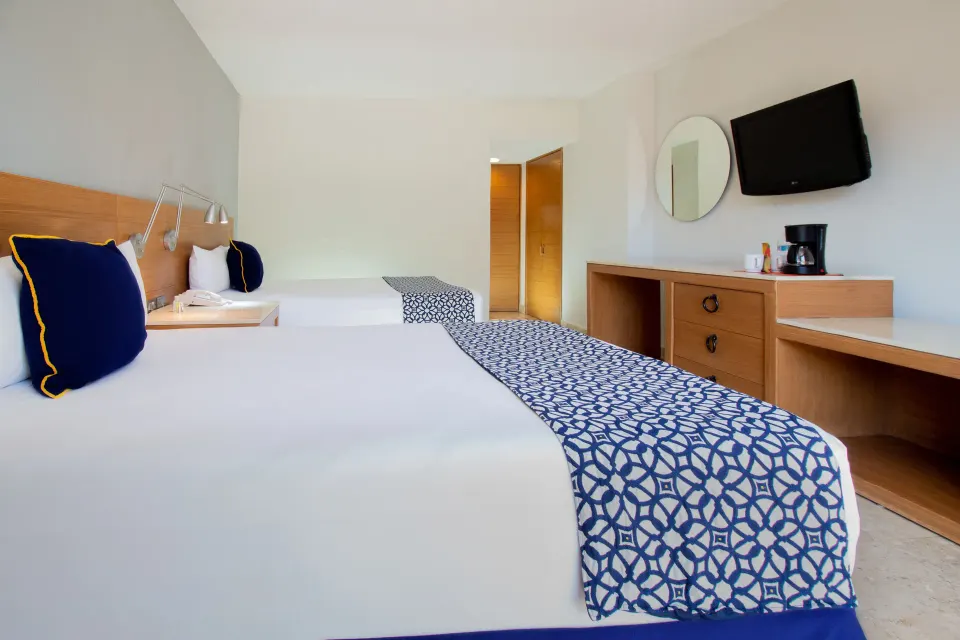 Superior Room beds with dresser, mirror, and coffee maker at Plaza Pelicanos Club Beach Resort.