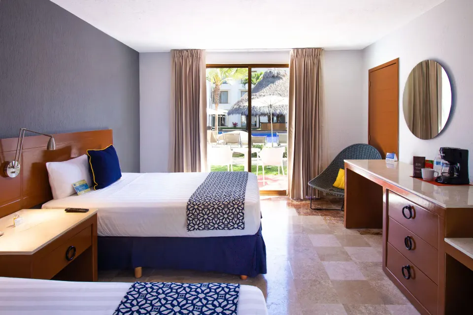 Superior Room with two beds, desk, and patio doors at Plaza Pelicanos Club Beach Resort.
