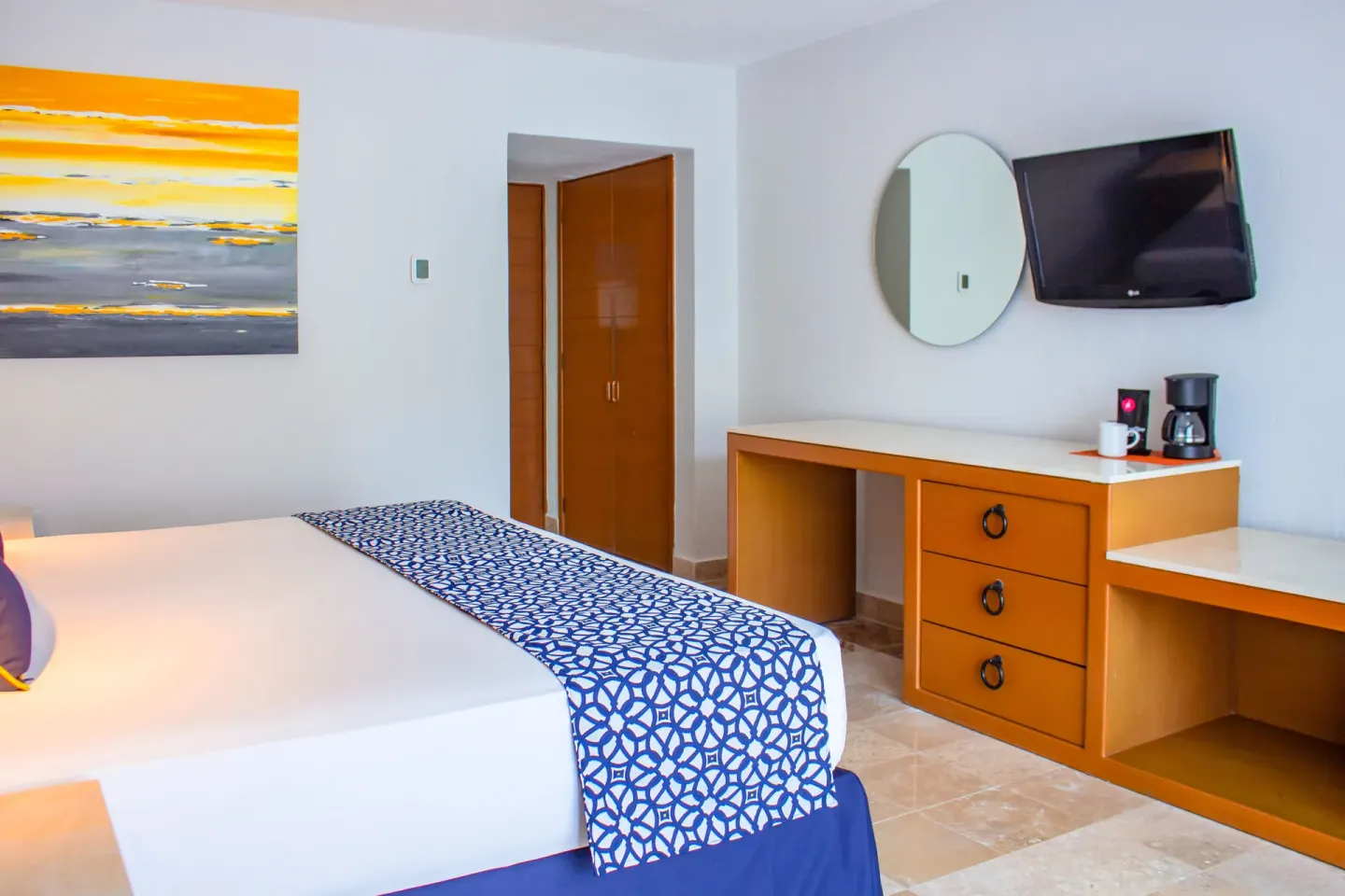 Superior king bed room at Plaza Pelicanos Club Beach Resort with dresser, TV, mirror, and coffee setup.