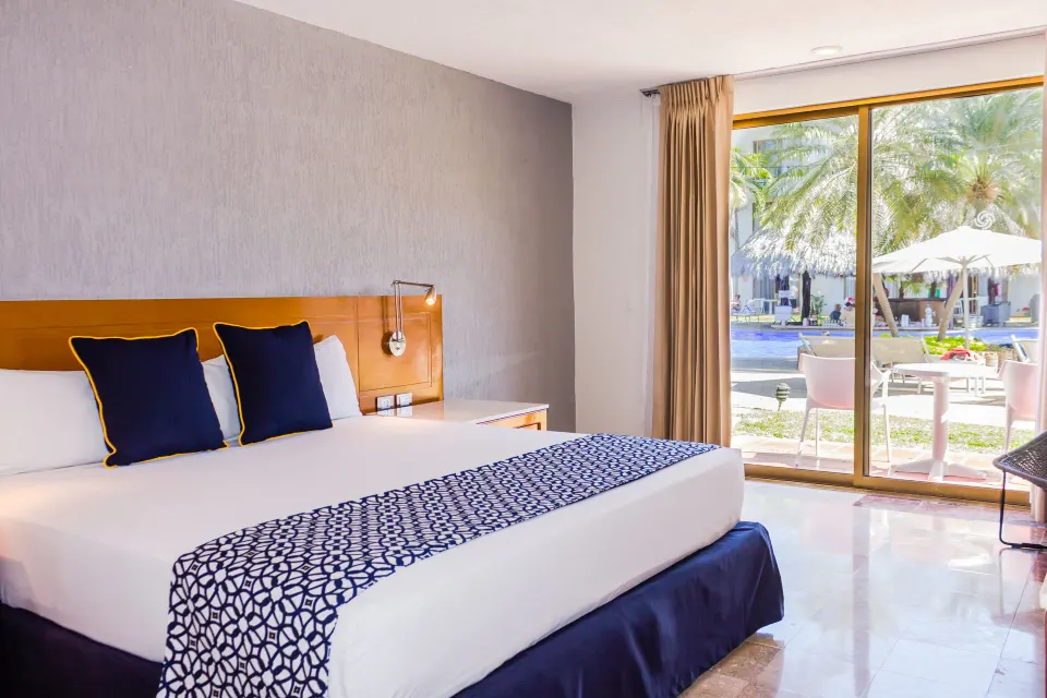 Superior king bed room at Plaza Pelicanos Club Beach Resort with sliding doors overlooking the pool area.