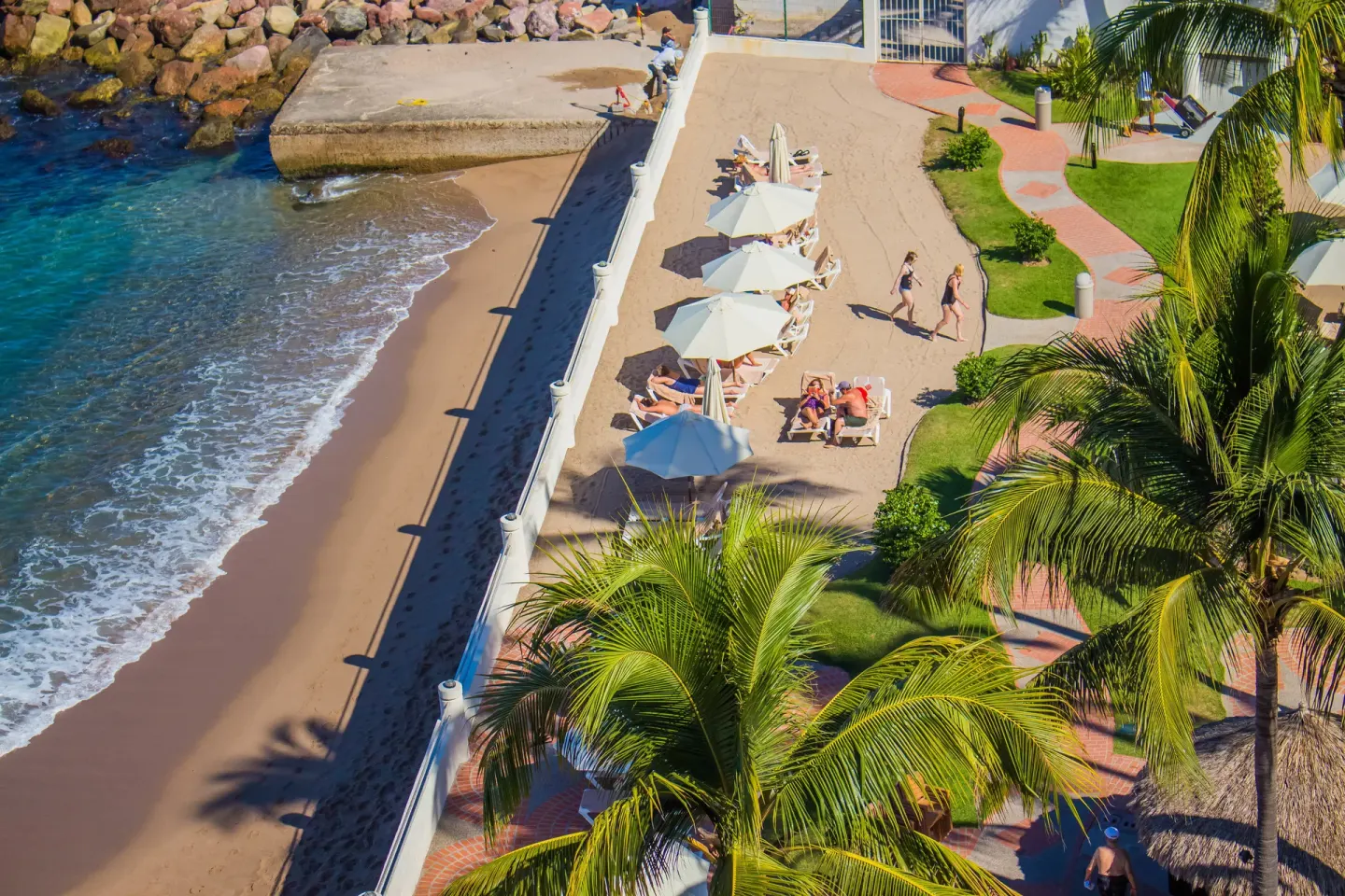 Beachfront promenade and umbrellas at Plaza Pelicanos Grand Beach Resort.