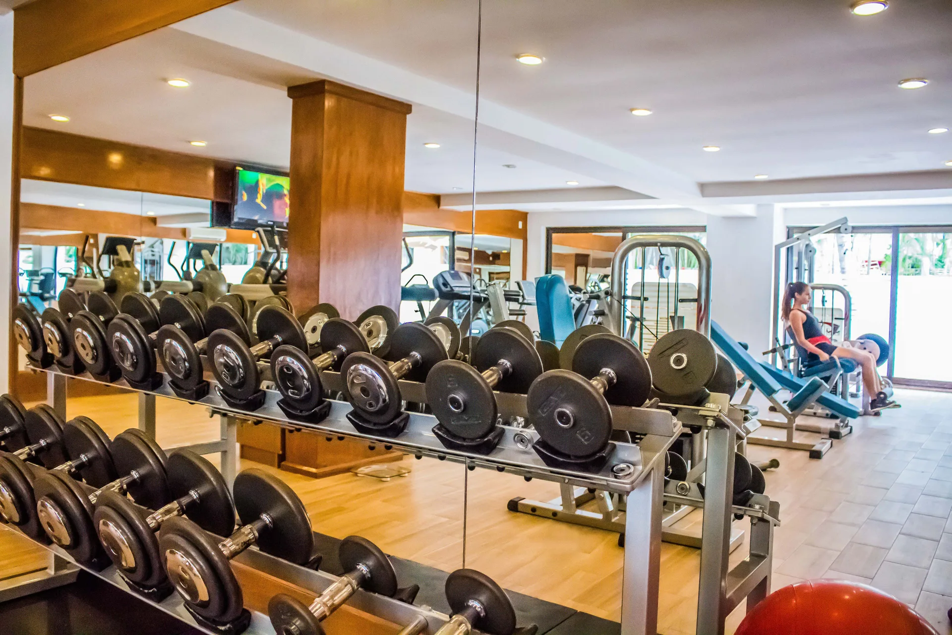 Dumbbell rack and strength machines in the fitness center at Plaza Pelicanos Grand Beach Resort.