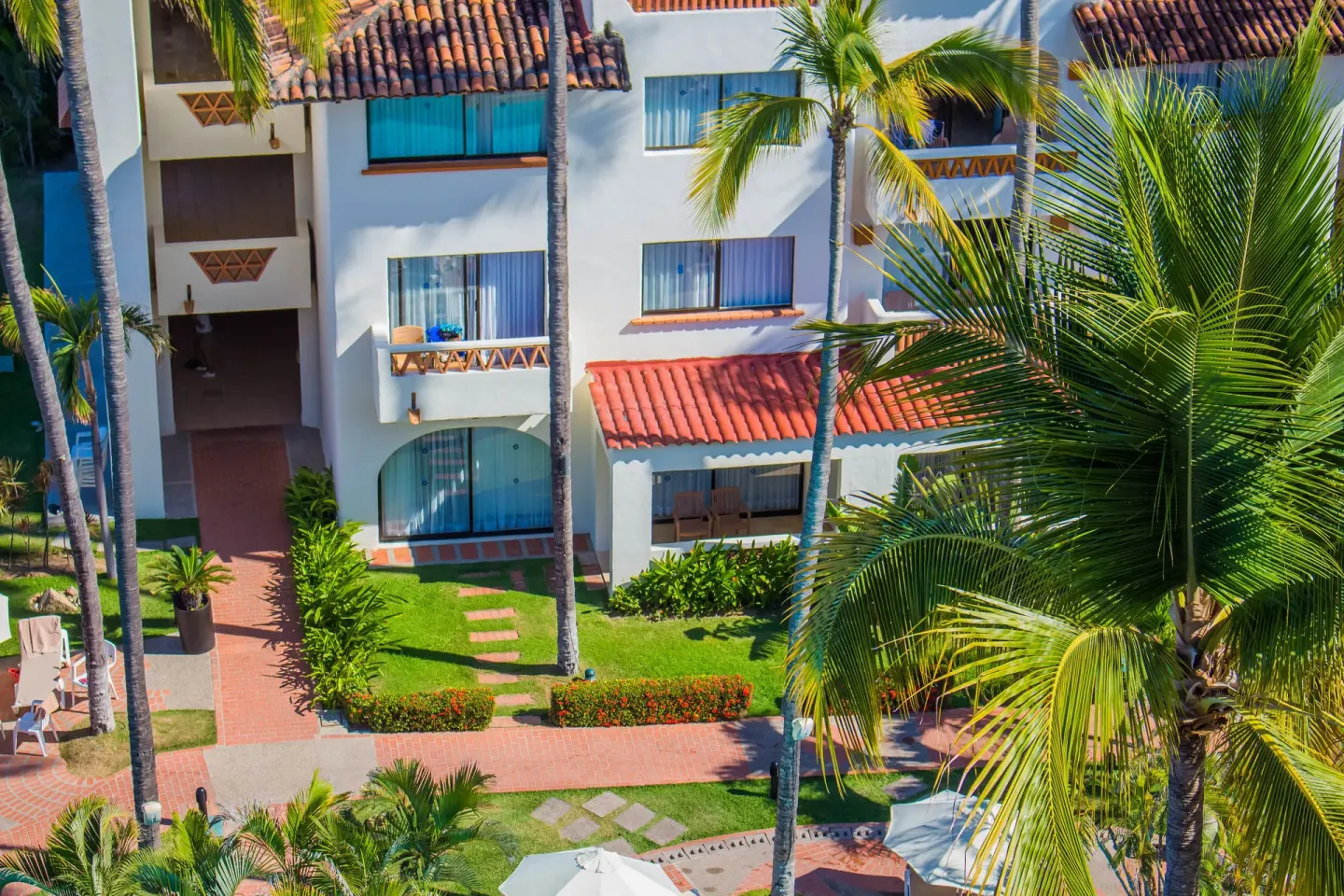 Palm-lined resort building and garden paths at Plaza Pelicanos Grand Beach Resort.