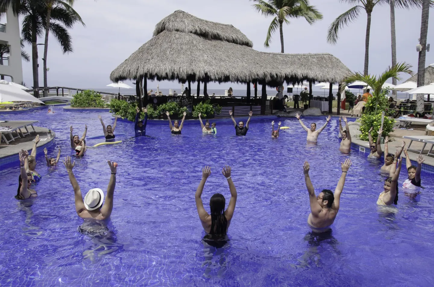 Guests doing a pool activity near a palapa at Plaza Pelicanos Grand Beach Resort.