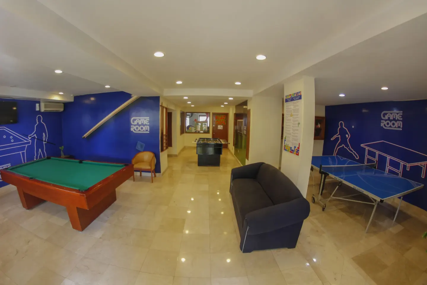 Wide game room with billiards, table tennis and seating at Plaza Pelicanos Grand Beach Resort.