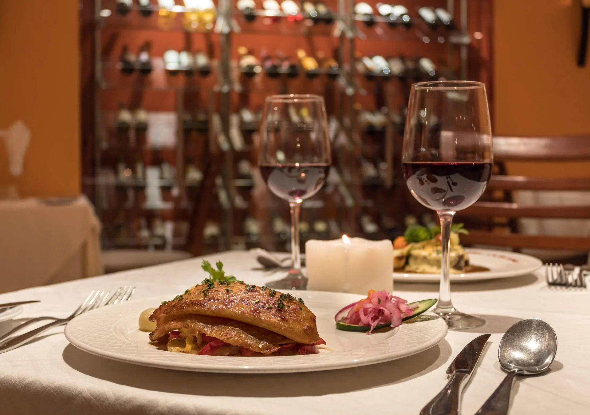 Plated entrée with red wine in a restaurant at Plaza Pelicanos Grand Beach Resort.