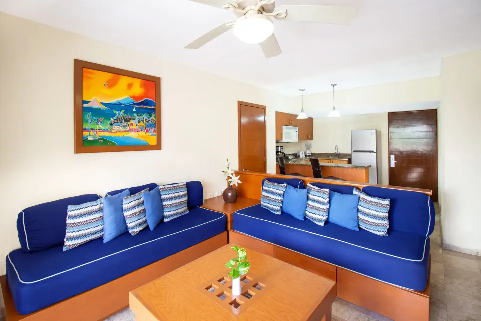 Suite living room with blue sofas and kitchenette at Plaza Pelicanos Grand Beach Resort.